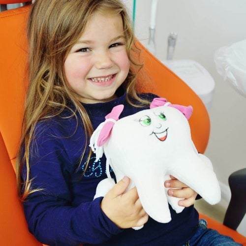 A,Little,Girl,Is,Sitting,Smiling,In,An,Orange,Dental